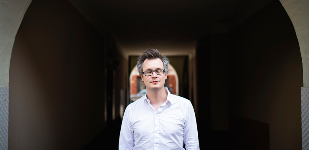 Säveltäjä Markku Klami kuvattuna kaarevan alikulkutunnelin edessä, silmät kiinni