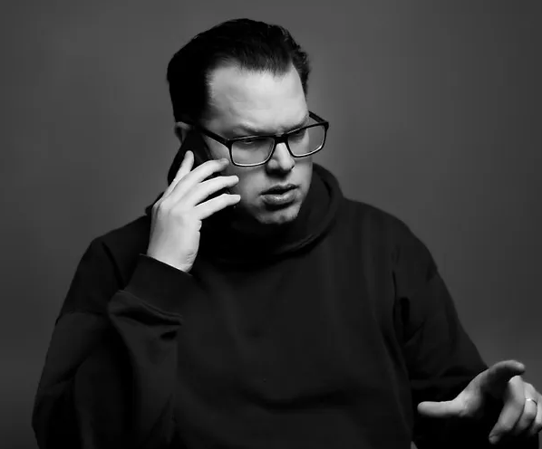 Mustavalkoinen kuva Jonas Olssonista puhumassa puhelimeen.